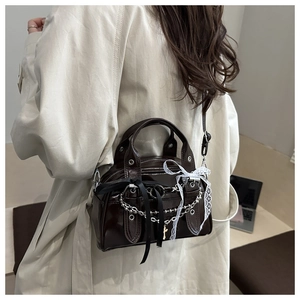 Detail of chocolate glossy small crossbody bag with silver chains and lace bows