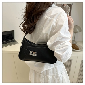 Detail view of a black minimalist underarm bag with silver buckle worn by a model
