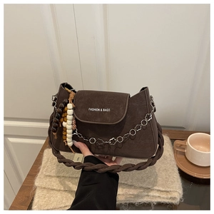 Gros plan d'un sac rétro en cuir marron avec bandoulière tressée et chaîne argentée