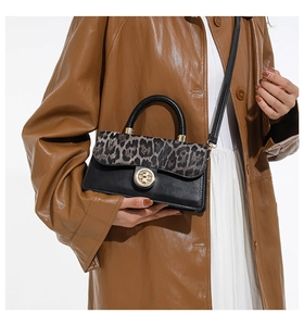 Close-up of leopard print patchwork crossbody bag with gold round metal twist lock