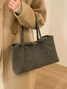 Grey matte leather tote bag for women shown with a camel coat in a stylish indoor setting