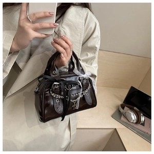 Detail of dark brown vintage Boston bag with silver chains, lace, and ribbon accents