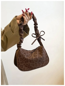 Detail of leopard print underarm bag featuring a ruched strap and small bow accent