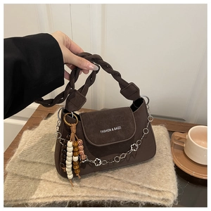 Détail du sac à bandoulière en daim marron avec poignée tressée et chaîne à fleurs