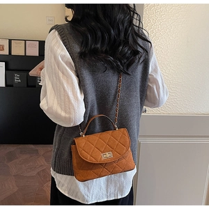 Detailed view of caramel brown quilted shoulder bag with gold twist lock and chain strap