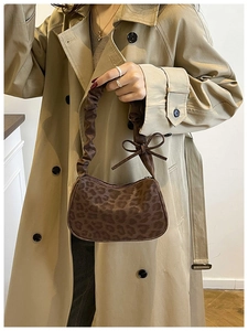 Detail of a brown leopard print crescent bag with suede texture and a cute bow