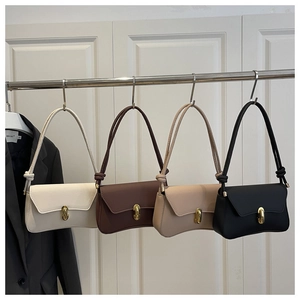 Row of minimalist leather underarm bags in white, brown, beige, and black on a rack