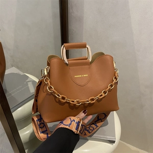 Brown leather bucket bag for women with gold chain and lettered strap on display