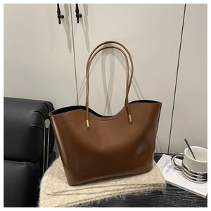 Detailed view of brown oil-wax leather tote bag with wavy rim and gold hardware accents