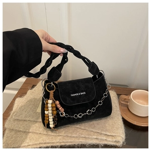 Détail du sac bandoulière en daim noir avec poignée tressée et chaîne fleurie
