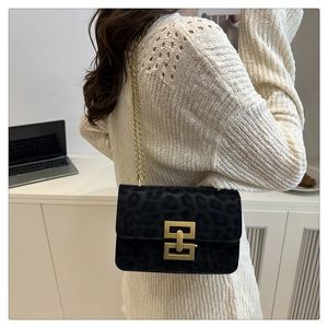 Detail of black leopard print crossbody bag with gold metal clasp and chain strap