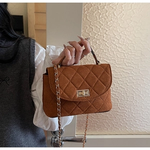 Close-up of brown quilted crossbody bag featuring a vintage golden twist lock and chain strap