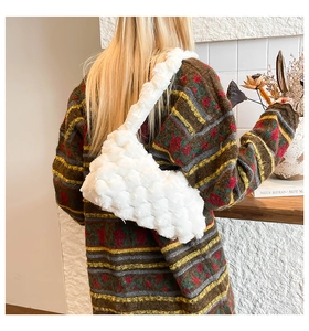 Primo piano della borsa tote in peluche bianca con trama a bolle indossata da un modello