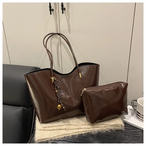 Detail of dark brown glossy leather tote bag with small pouch and golden sphere charm