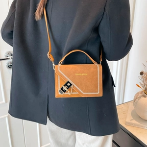 Caramel brown suede shoulder bag with chain strap and stitch detail shown on model