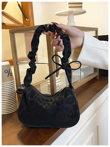 Detail of black leopard print underarm bag with ruffled handle and bow decoration