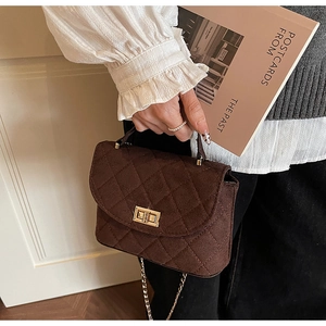 Detail of dark brown quilted crossbody bag with gold twist lock and chain strap