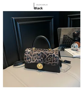 Detail of leopard print flap and gold twist-lock on a black leather crossbody bag