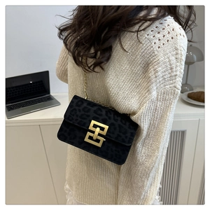 Detail of leopard print suede crossbody bag with gold chain strap worn by a model