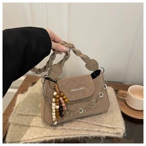 Détail du sac beige avec poignée tissée et chaîne métallique à fleurs décoratives