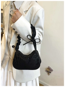 Close-up of black ruched shoulder bag with bow detail and textured matte finish