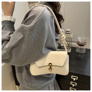 Close-up of cream leather shoulder bag with oval gold buckle and adjustable strap