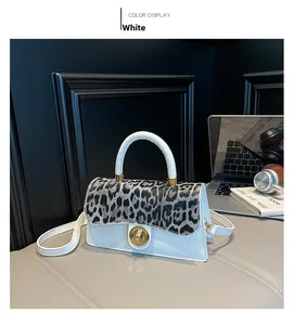 Close-up of stylish white square bag featuring leopard print flap and gold twist lock