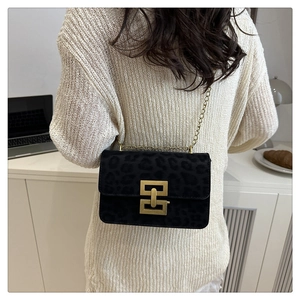 Detail of a chic leopard print square bag with a golden geometric buckle and chain strap