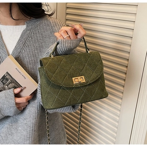 Detail of dark green quilted crossbody bag with golden clasp and chain strap