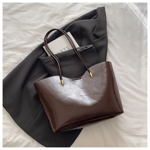 Close-up of dark brown oil wax leather tote bag with elegant gold metal strap accents