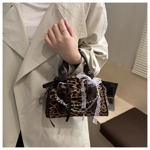 Detail of leopard print handbag with silk bow, silver chain and white lace trim