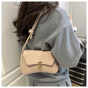 Minimalist beige crossbody bag on model showing strap knot detail and gold lock