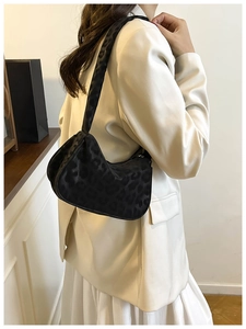 Detail view of black leopard print suede shoulder bag styled with elegant office wear