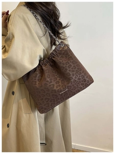 Detail of leopard print tote bag with silver chain strap worn with a trench coat