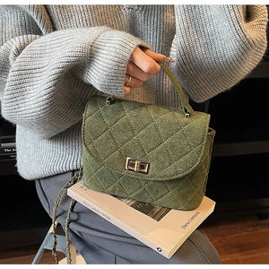 Macro detail of dark green quilted suede bag with gold twist lock on grey sweater