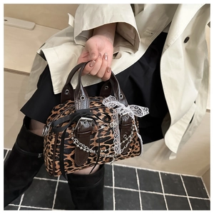 Detail of leopard print handbag with silver chain, lace bow and brown leather trim