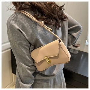 Detail of minimalist beige leather shoulder bag with gold twist lock and curved bottom