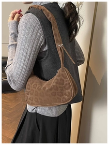 Detail of leopard print suede baguette bag with silver hardware and wide shoulder strap