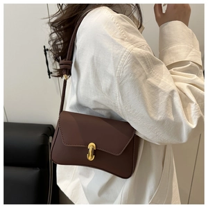 Detail view of a vintage brown leather crossbody bag with a golden U-shaped buckle