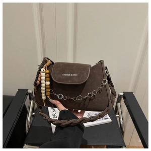 Détail du sac bandoulière marron mat avec sangle tissée et breloque bohème perlée
