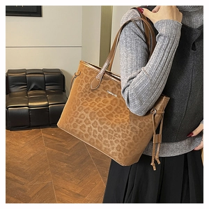 Détail du sac cabas à imprimé léopard avec pompon à cordon et logo blanc lettré