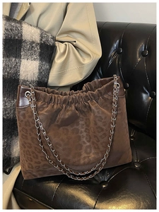 Detail of leopard print tote bag featuring metallic chain strap and textured fabric