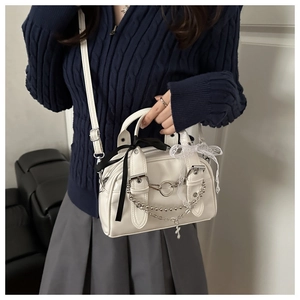 Detail view of white vintage mini bag featuring punk metal chains and lace ribbons