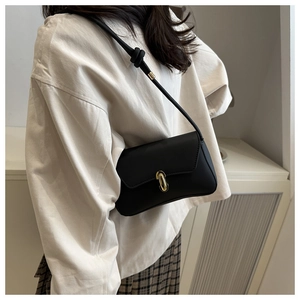 Close-up of black crossbody bag with golden twist lock and knot shoulder strap detail