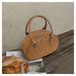 Detail of a brown frosted texture Boston bag with subtle leopard pattern on a wooden desk