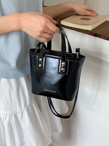 Chic black glossy leather bucket bag with gold hardware and removable shoulder strap