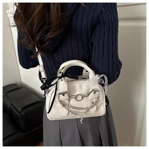 Detail of white Boston mini bag featuring silver chains and decorative ribbon bows