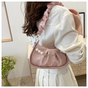 Detail of pink pleated cloud bag featuring pearl flower chain and ruffled shoulder strap