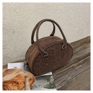 Close-up of brown matte boston bag with leopard embossing on a rustic tabletop