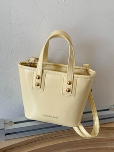 Chic pale yellow patent leather mini bucket bag with gold studs and crossbody strap
